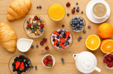 Fototapeta premium Continental breakfast with croissants and berries on natural wood