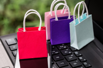 Colorful paper shopping bags with mobile phone on a laptop keyboard. Concept about online shopping that customers can buy everything from home or office. Via the tool electronics.