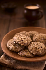 Homemade double chocolate chip cookies on rustic plate, photographed on dark wood with natural light (Selective Focus, Focus one third into the cookie on the top)