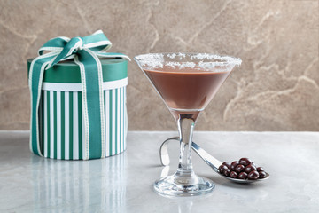 chocolate shake in a glass with a high stem on the background of gift boxes with bow