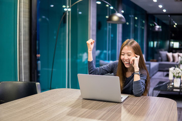 Beautiful Asian girl celebrate with laptop, using hands in different positions, education or technology or startup business concept, modern office or living room with copy space