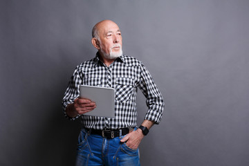 Senior man reading news on digital tablet