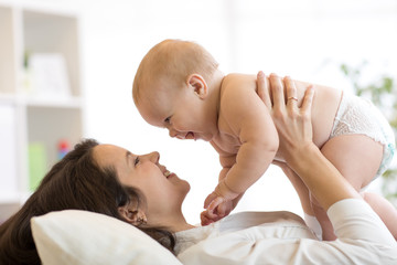 Mother and baby hugging and playing lying indoors