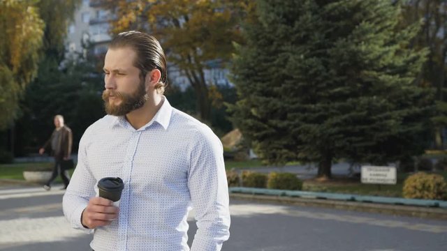 Handsome man drinks a coffee and waits on the street. 4K