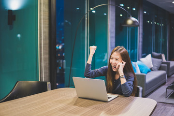 Beautiful Asian girl celebrate with laptop, using hands in different positions, education or technology or startup business concept, modern office or living room with copy space vintage tone
