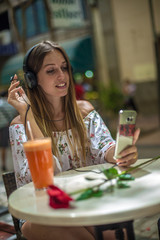 Romantic cute girl is sitting in the cafe and video chatting with red rose on the table. Dating and love concepts. Human emotions.