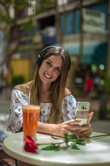 Romantic cute girl is sitting in the cafe and video chatting with red rose on the table. Dating and love concepts. Human emotions.