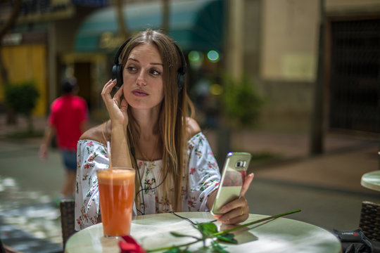 Romantic cute girl is sitting in the cafe and video chatting with red rose on the table. Dating and love concepts. Human emotions.