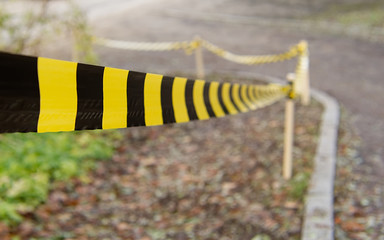Barrier tape downhill in an autumn setting. Parts of the road is visible.
