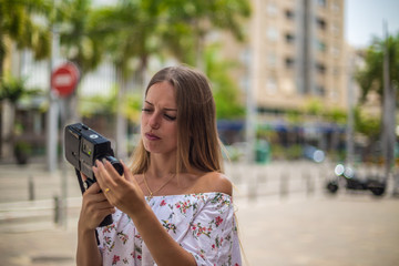 Tenerife. Spain. Cute blonde girl is observing and  filming streets in Santa Cruz de Tenerife. Girl travels concept. Travel to Canary Islands.