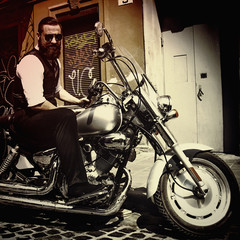 Naklejka na ściany i meble Serious Bearded Biker Man Sitting on a Motorcycle