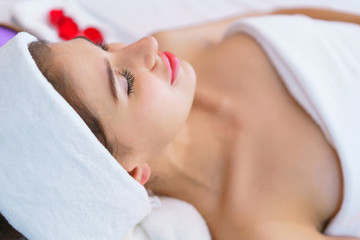 Young beautiful woman lying on the bed with happy spa body and scrub skin at spa salon. concept of relaxing health aroma spa, treatment and body massage.