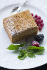 Slice of layered honey cake with leaf of mint