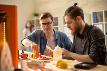 Portrait of two young men using 3D printer studying creative design and architecture in college