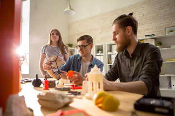 Portrait of three young people using 3D printer working on creative design project together studying architecture in college