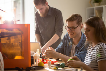Portrait of three creative young people enjoying work with 3D printer in modern design studio, copy space