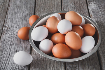 Fresh brown eggs in bowl on wood background