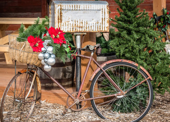 Fototapeta na wymiar horizontal Christmas image of a very old rusty bike decorated with Christmas decoration and silver balls leaning against an old Tin mailbox.
