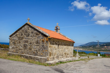 Fototapeta na wymiar Historic village medieval church by the asphalt road during sunny day, blue sky