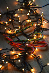 Candy canes lying on the wooden floor with christmas lights.