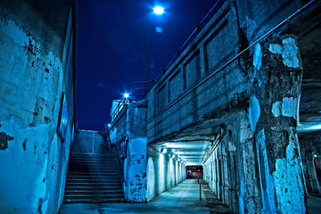 Gritty dark Chicago city street under industrial bridge viaduct tunnel with a stairway to Metra...