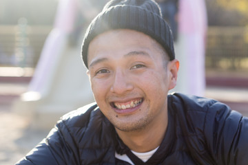 ット帽の日本人男性が屋外で笑顔になるポートレート｜親しみやすいプロフィール・ビジネス素材