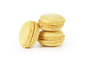 three yellow lemon macarons isolated on white