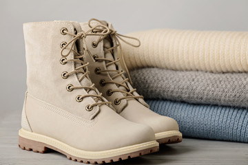 Leather women's light winter boots and a pile of knitted things (sweaters, scarves, gloves).