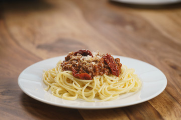 spaghetti bolognese on white plate on wood table