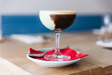 Coffee cocktail with green paste in wine glass on red napkin and plate.