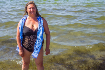 Fototapeta na wymiar A woman stands on in water resting on summer on a sea