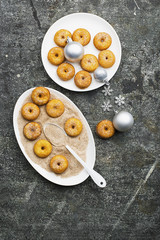 Appetizing ruddy traditional donuts with sugar and cinnamon on an oval dish on a gray grunge trendy background with a Christmas graceful neat decor with silver stars and a garland. Top View.