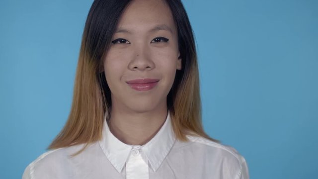 close up portrait young asian woman on blue background in studio. attractive millennial girl looking at the camera