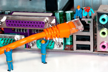 Computer Network Internet Cable - Miniature construction worker figurines posed as if working on a network connection.