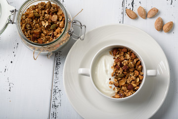 Healthy breakfast: Greek yogurt with homemade granola in a white bowl and jar with granola
