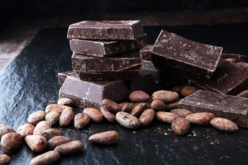 Dark chocolate pieces, stacks and cocoa beans, culinary background..