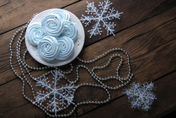 Blue mini meringues and  christmas decorations on a wooden background