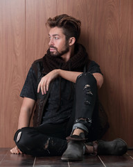 Handsome mature man sitting by the brick wall. Men's fashion.