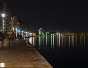Fototapeta premium Thessaloniki, Greece night view of The White Tower and surrounding waterfront. The city's landmark seen from Christmas illuminated old waterfront area. 