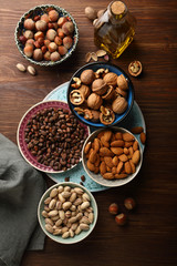 Assorted nuts in bowls on wood background