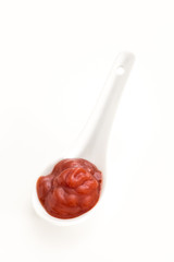 Creamy red sauce in white ceramic spoon, on white background.