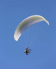 wide Motor powered hang glider flies high in the blue sky
