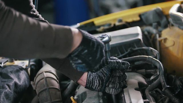 Car auto service - mechanic unscrews detail of car
