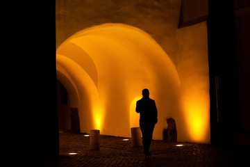 silhouettes of people walking  in night lit passage way