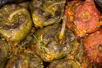 Stuffed green bell peepers and tomatoes in dish, closeup background.