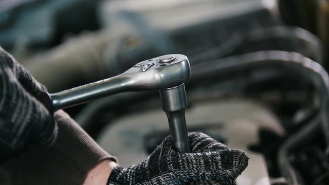 Car auto service working - mechanic unscrews detail of car