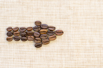 Coffee grains are lined in the form of an arrow on a beige napkin.