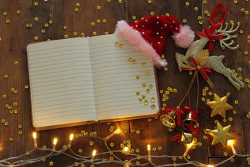 Top view image of christmas festive decorations next to empty open notebook on old wooden background