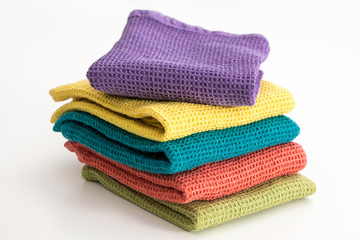 Stack of neatly folded colorful kitchen towels, on white background.