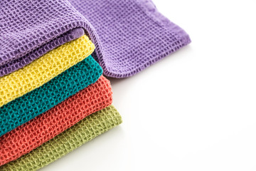 Stack of neatly folded colorful kitchen towels, on white background.